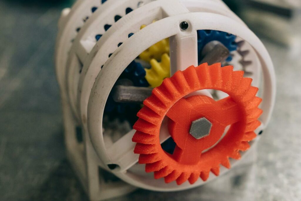 A close-up photo of a 3D printed gear mechanism on a metallic workbench, highlighting innovation and technology.