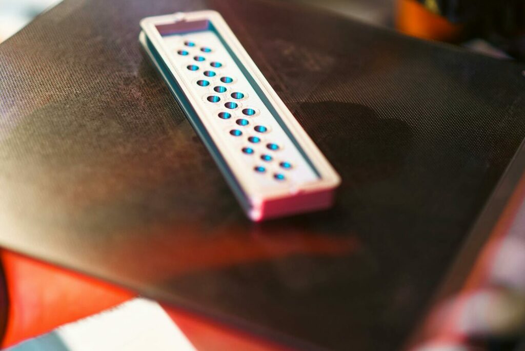 Close-up of a 3D printed part on an industrial printer in a workshop setting.